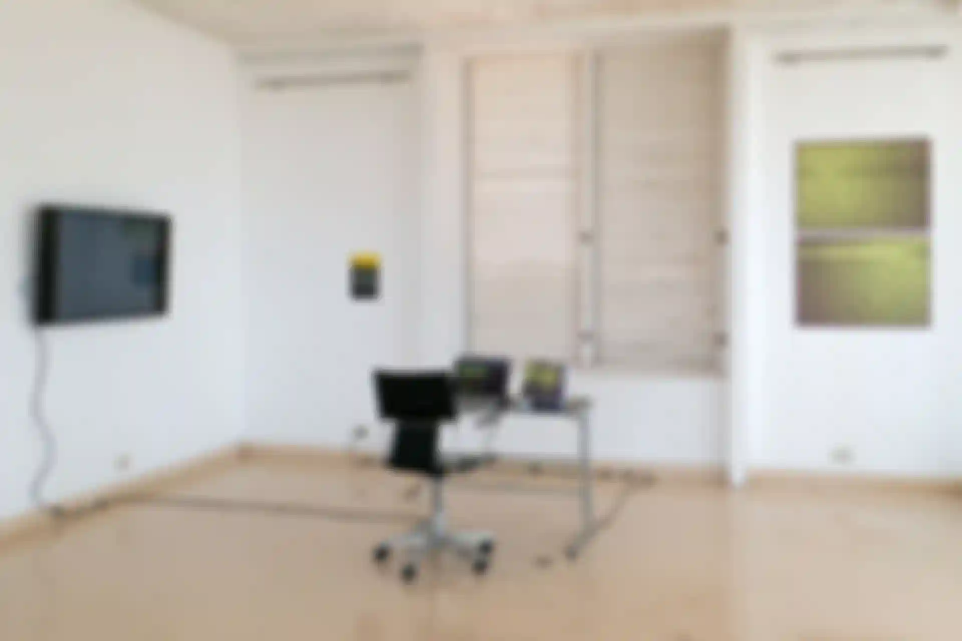 Ein Tisch in der Mitte eines Raumes. Auf dem Tisch stehen ein Laptop, auf dem die Website von Creative Pattern Recognition zu sehen ist, und zwei gedruckte Exemplare der Publikation. An der Wand daneben hängt ein Fernseher, auf dem der Bildschirm des Laptops übertragen wird. An der Wand hinter dem Tisch hängen zwei Poster.