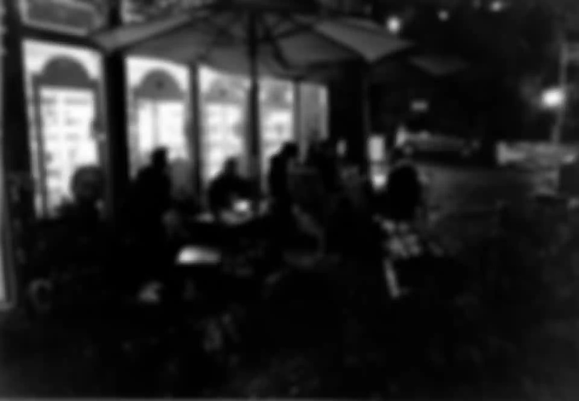 Gruppen von Menschen, die vor einem Kiosk an Tischen sitzen.